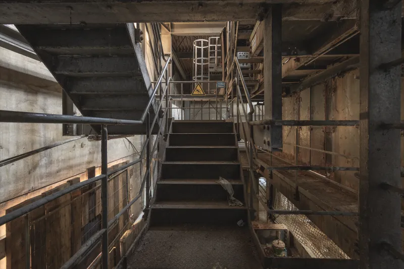 Verlassene Industrieanlage mit rostiger Metalltreppe und alten Geländern in maroder Fabrikumgebung  
